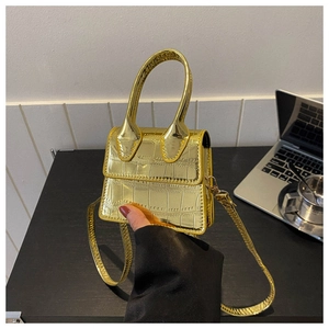 Detail of yellow crocodile pattern leather handbag with gold handle and shoulder strap