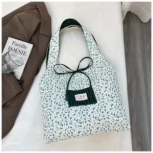 Detailed view of floral canvas tote bag with green checkered pocket and bow tie closure