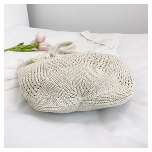 Macro detail of creamy white hand-woven crochet bag with texture and fringe detail