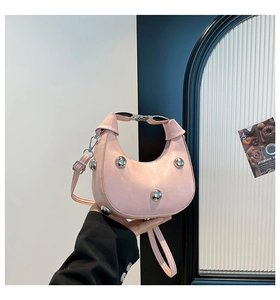 Borsa a mezzaluna rosa con borchie argento e tracolla regolabile tenuta in mano