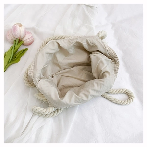 Macro view of woven tote interior with beige lining, thick rope handles and tassel detail