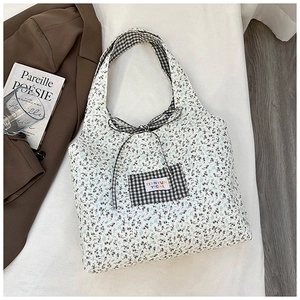 Detail of floral canvas tote bag featuring a checkered bow and front patch pocket