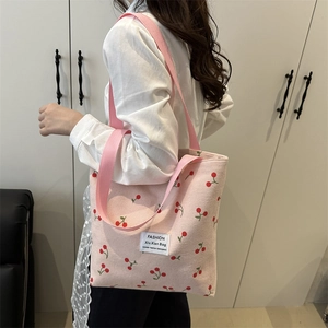 Pink corduroy tote bag with cherry print shown on model for daily casual style