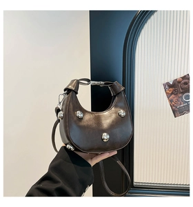 Dettaglio borsa a mezzaluna marrone scuro con borchie metalliche e tracolla