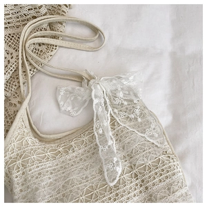 Gros plan sur un tissu en dentelle crochetée blanche avec motifs floraux et nœud