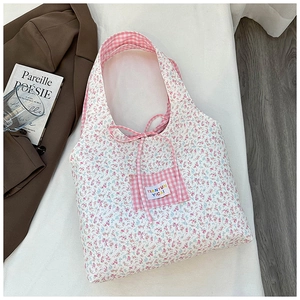 Detail of floral tote bag showing pink plaid pocket and elegant ribbon tie accents