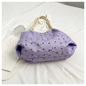 Top view of a light purple tote bag with black bow patterns and rope handles