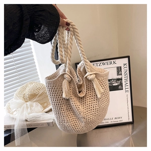 Detailed macro view of woven hollow-out handbag with fringe tassel and thick rope handle