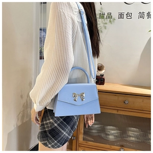 Detail of light blue crossbody bag with silver bow ornament on a vintage background