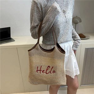 Straw tote bag with brown leather handles and red Hello embroidery in summer style