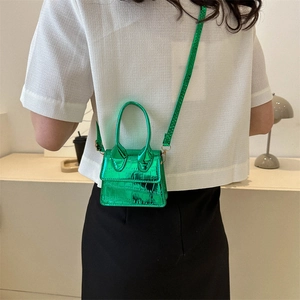 Mini green faux crocodile crossbody bag with top handles shown on model in a cozy setting