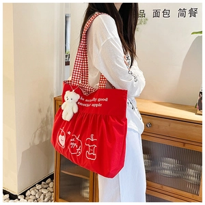 Detail of red canvas tote bag with gingham handles and cute plush bear charm