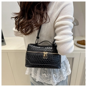 Detail of black woven box bag showing premium leather texture and golden zippers