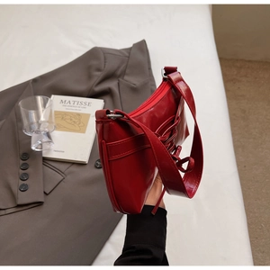 Détail du sac à bandoulière en cuir verni rouge avec laçage décoratif et zip argenté
