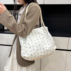 White pleated tote bag with black bow print and thick cotton rope handles shown on shoulder