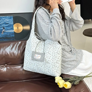 Floral canvas tote bag with plaid pocket and drawstring closure shown in a lifestyle setting