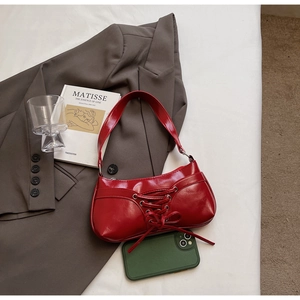 Détail d'un sac à bandoulière en cuir verni rouge avec un laçage décoratif élégant et chic