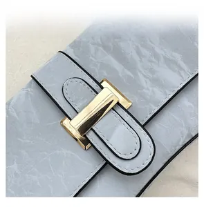 Detail view of golden rectangular buckle on light blue marble texture leather bag