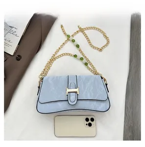 Detail of light blue textured leather bag with gold chain strap and pearl bead accents