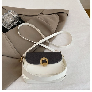 Détail du sac bandoulière minimaliste noir et blanc avec une boucle dorée en fer à cheval