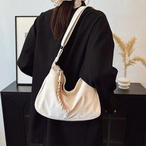 Minimalist cream white hobo bag with colorful woven charms worn with black blazer