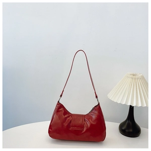 Detail of dark red vintage shoulder bag with glossy leather texture on white table