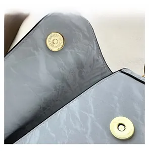 Detail showing the magnetic buckle closure on a textured light blue faux leather bag