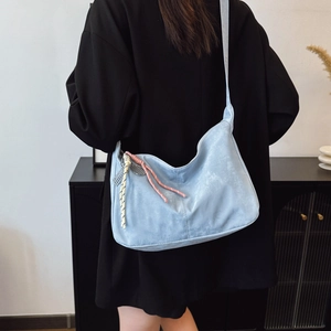 Light blue large capacity shoulder tote bag with woven pendant shown on model