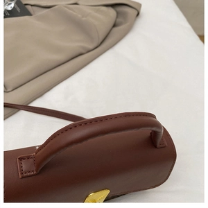 Close-up of vintage dark brown handbag with golden metal lock and leather handle