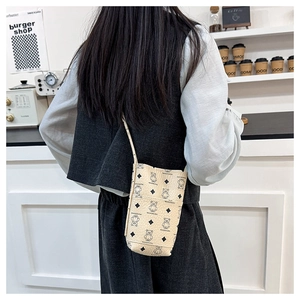 Chic beige crossbody phone bag with bear print shown on model in a modern cafe setting