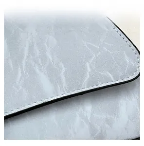 Detailed close-up of precise black stitching on light blue marble pattern leather