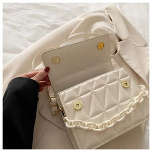 Detail of white quilted crossbody bag with golden magnetic clasp and chunky chain strap
