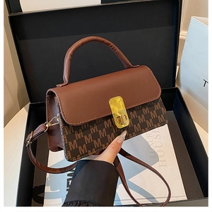 Detail of brown monogram shoulder bag with gold metal lock inside luxury gift box