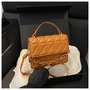 Detail of bright orange crossbody bag with large diamond stitching and gold chain decoration