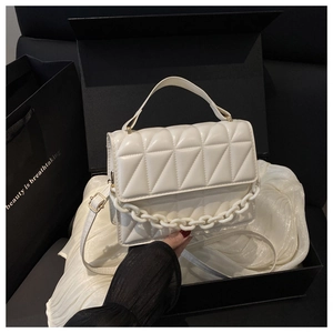 Detail of cream quilted handbag with chunky resin chain and leather strap in a gift box