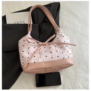 Macro view of pink handbag with floral pleats and black bow accents on a blazer