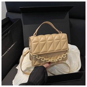 Close-up of beige geometric quilted PU leather handbag with decorative thick chain detail