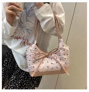 Detail of light pink quilted handbag featuring black bow patterns and large front bow tie