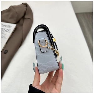 Side view detail of a light blue pleated handbag with gold D-ring and chain hardware