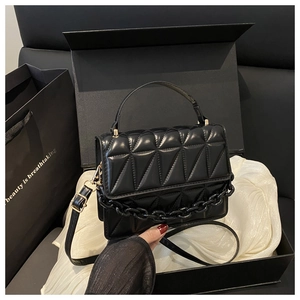 Detail of black glossy small square bag with 3D triangle stitching and chain