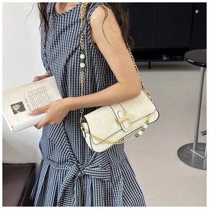 Detail of off-white cracked leather shoulder bag with gold H-buckle and beaded chain strap