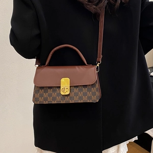 Retro brown leather handbag with M-letter print and gold lock shown on black blazer
