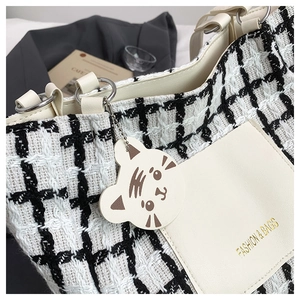 Detail of checkered tote bag with gold-stamped fashion text and leather side pocket