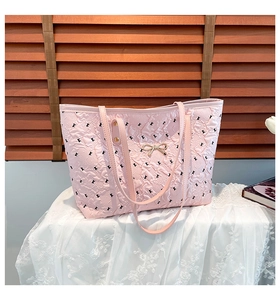 Detailed shot of pink quilted tote bag featuring a delicate gold metal bow and long straps