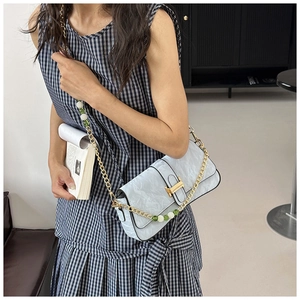 Detail of light blue pleated PU leather bag with gold H-buckle and pearl chain strap