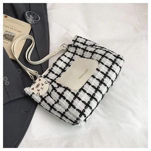 Detail of tweed checkered tote bag with white leather pocket and cute cat charm decoration