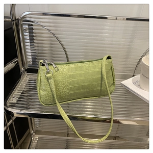 Detailed view of crocodile pattern texture and silver zipper on avocado green baguette bag
