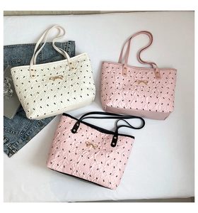 Detail of embossed tote bags with black bow prints and gold hardware accents