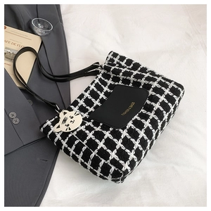 Macro view of plaid tote bag with black leather front pocket and fashion logo