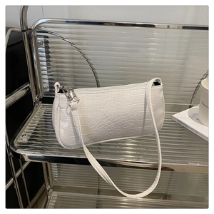 Close-up of white crocodile skin texture on a minimalist baguette shoulder bag with silver zip